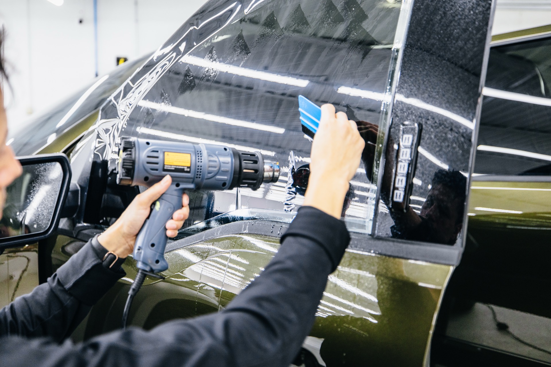 Heat gun work on rear quarter window during tint installation